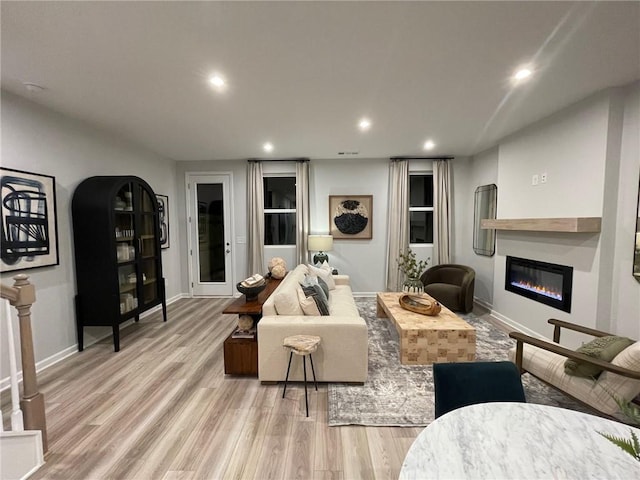 living room with recessed lighting, baseboards, wood finished floors, and a glass covered fireplace