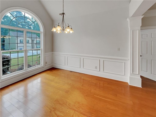 6405 Beaver Creek Trl, Atlanta, GA 30349 - unfurnished dining area with light wood-type flooring, a wainscoted wall, lofted ceiling, an inviting chandelier, and a decorative wall
