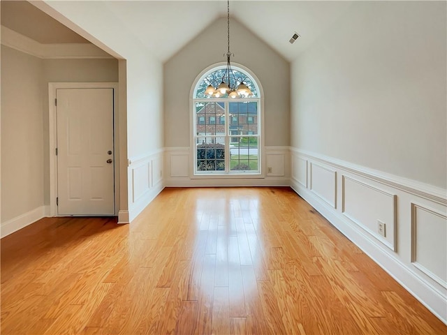 6405 Beaver Creek Trl, Atlanta, GA 30349 - unfurnished dining area with light wood-style floors, vaulted ceiling, a wainscoted wall, an inviting chandelier, and a decorative wall