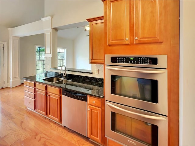 6405 Beaver Creek Trl, Atlanta, GA 30349 - kitchen featuring appliances with stainless steel finishes, a sink, dark stone countertops, lofted ceiling, and light wood-type flooring