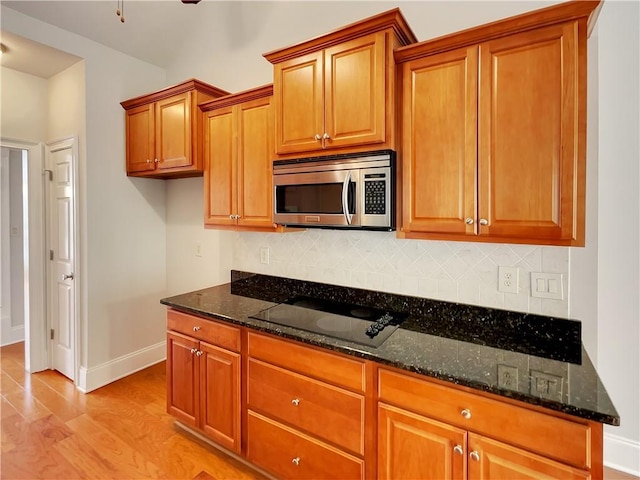 6405 Beaver Creek Trl, Atlanta, GA 30349 - kitchen with baseboards, black electric stovetop, stainless steel microwave, brown cabinets, and dark stone countertops