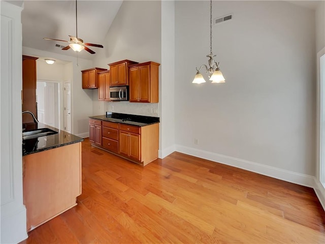 6405 Beaver Creek Trl, Atlanta, GA 30349 - kitchen with light wood-style floors, stainless steel microwave, brown cabinets, a sink, and ceiling fan with notable chandelier