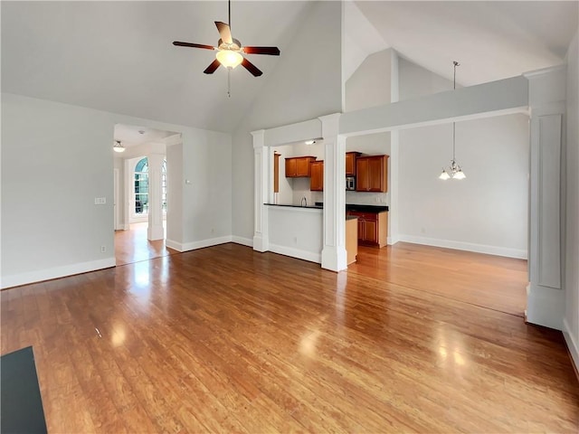 6405 Beaver Creek Trl, Atlanta, GA 30349 - unfurnished living room with baseboards, light wood-style flooring, ceiling fan with notable chandelier, and high vaulted ceiling