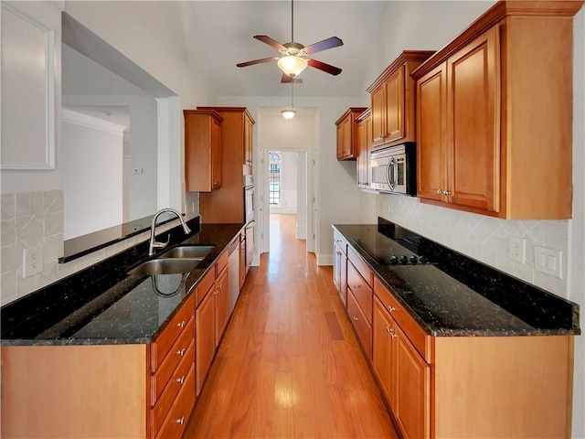 6405 Beaver Creek Trl, Atlanta, GA 30349 - kitchen with brown cabinetry, a ceiling fan, a sink, light wood finished floors, and stainless steel appliances