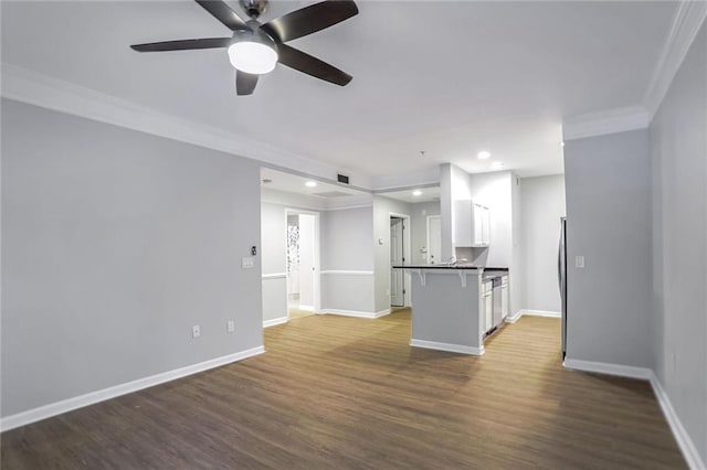 unfurnished living room featuring ceiling fan, ornamental molding, and dark wood-type flooring