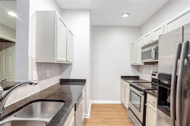 kitchen featuring dark stone counters, sink, decorative backsplash, appliances with stainless steel finishes, and white cabinetry