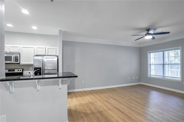 kitchen with white cabinets, electric stove, decorative backsplash, stainless steel fridge with ice dispenser, and a breakfast bar area