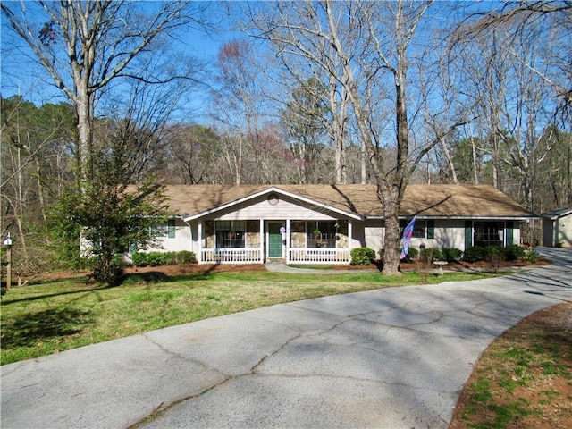 ranch-style home with driveway, a front lawn, and a porch