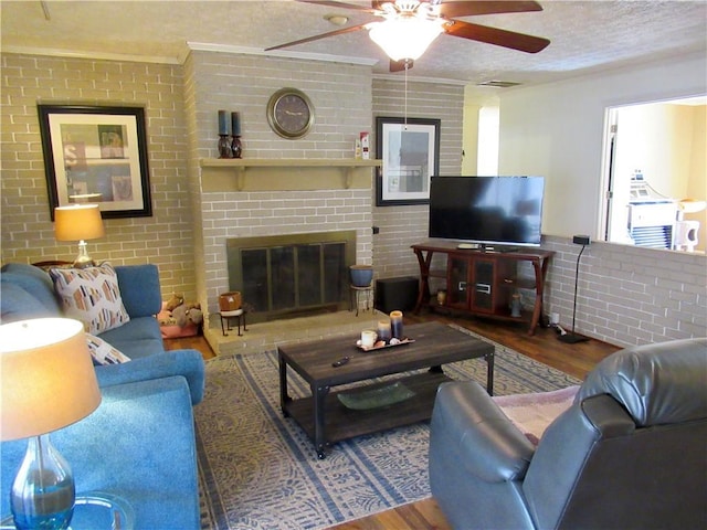 living room with a brick fireplace, brick wall, and wood finished floors