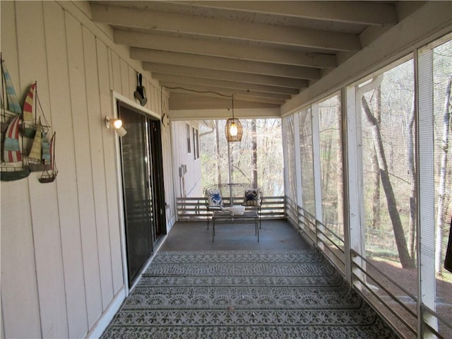 unfurnished sunroom featuring vaulted ceiling with beams