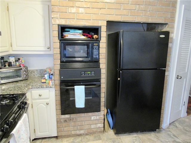 kitchen featuring black appliances, a toaster, white cabinetry, and light stone counters