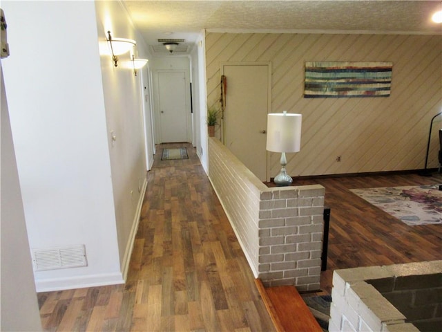 hallway with baseboards, crown molding, visible vents, and wood finished floors