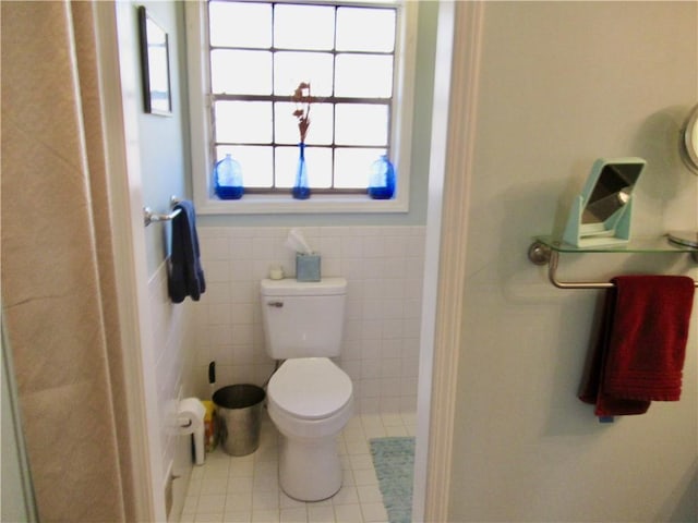 full bath with toilet, a wainscoted wall, tile walls, tile patterned floors, and walk in shower