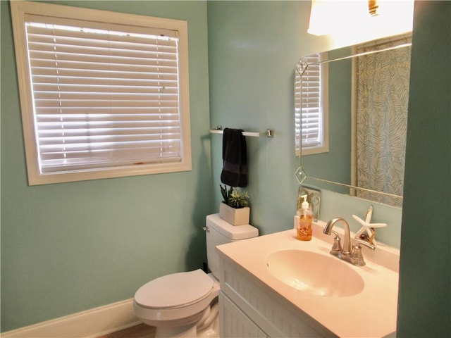 bathroom with toilet, a healthy amount of sunlight, curtained shower, and vanity