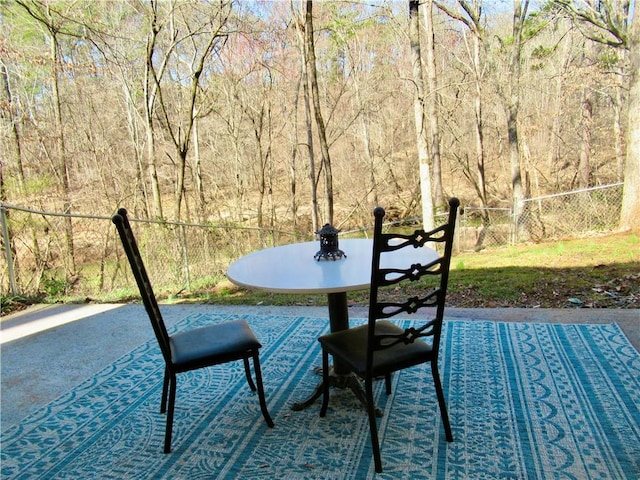 view of patio / terrace featuring a wooded view and fence