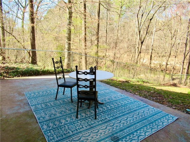 view of patio featuring a forest view and fence