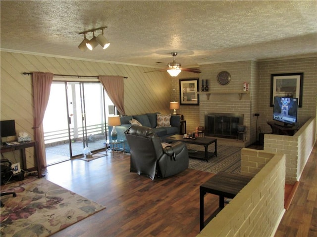 living room with ceiling fan, a fireplace, a textured ceiling, and wood finished floors