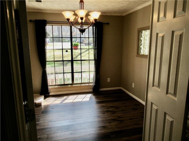 unfurnished dining area with a textured ceiling, dark wood-style flooring, baseboards, ornamental molding, and an inviting chandelier