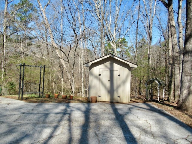 view of shed featuring a gate and a view of trees