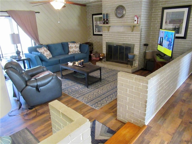 living room featuring ceiling fan, a fireplace, and wood finished floors