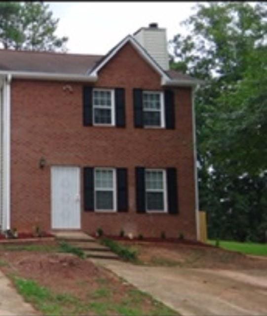 view of front of house featuring a chimney and brick siding