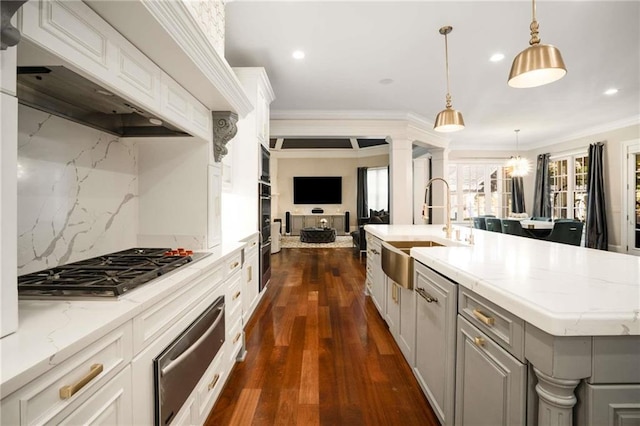 kitchen with crown molding, a warming drawer, appliances with stainless steel finishes, open floor plan, and a sink