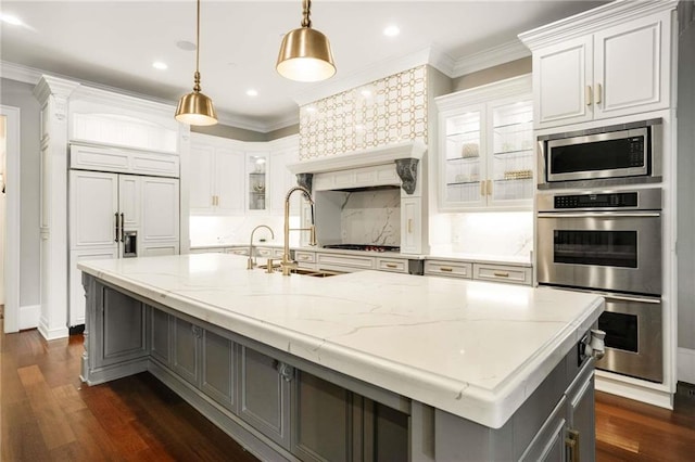 kitchen featuring stainless steel appliances, backsplash, a sink, and dark wood finished floors