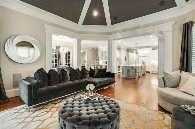 living room featuring crown molding, decorative columns, and wood finished floors