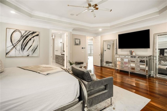 bedroom with connected bathroom, wood finished floors, a ceiling fan, ornamental molding, and a tray ceiling