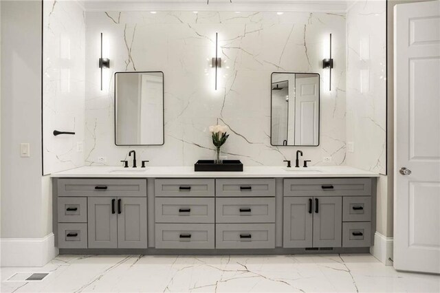 ensuite bathroom featuring marble finish floor, ornamental molding, a sink, and a notable chandelier