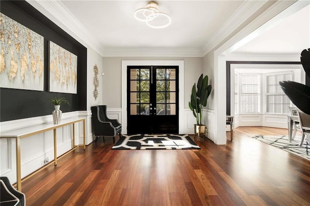 foyer featuring wood finished floors, a decorative wall, crown molding, and french doors