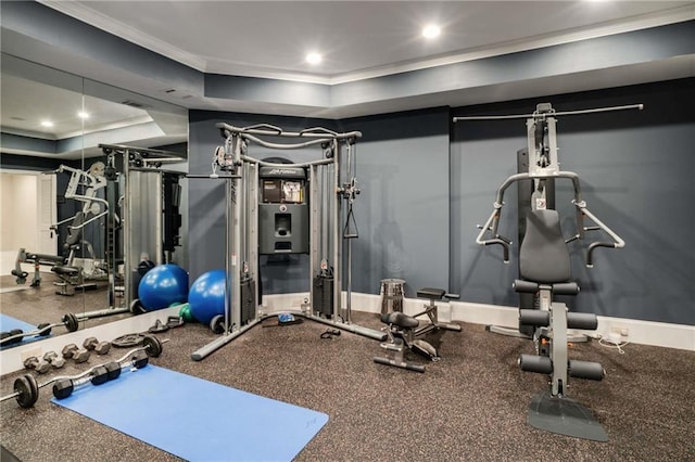 exercise area featuring a tray ceiling, baseboards, crown molding, and recessed lighting