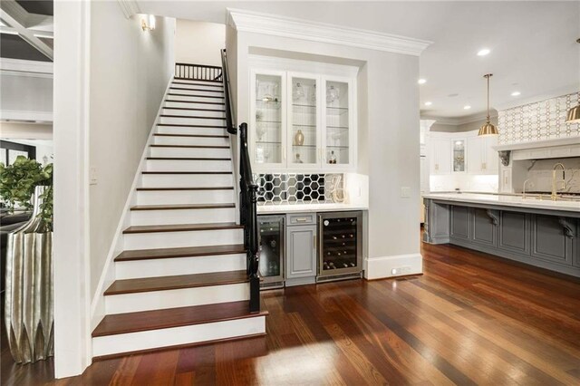 staircase with baseboards, ornamental molding, wood finished floors, and recessed lighting