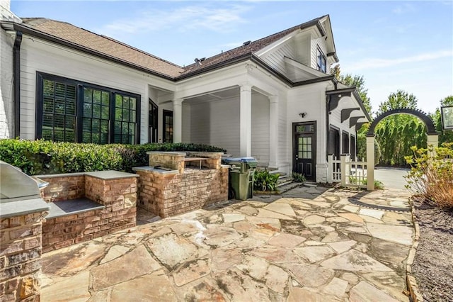 view of patio featuring exterior kitchen and a grill