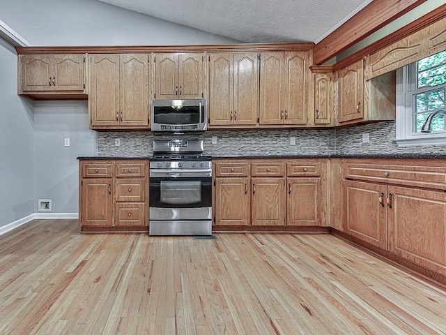 kitchen with backsplash, stainless steel appliances, light hardwood / wood-style floors, and a textured ceiling