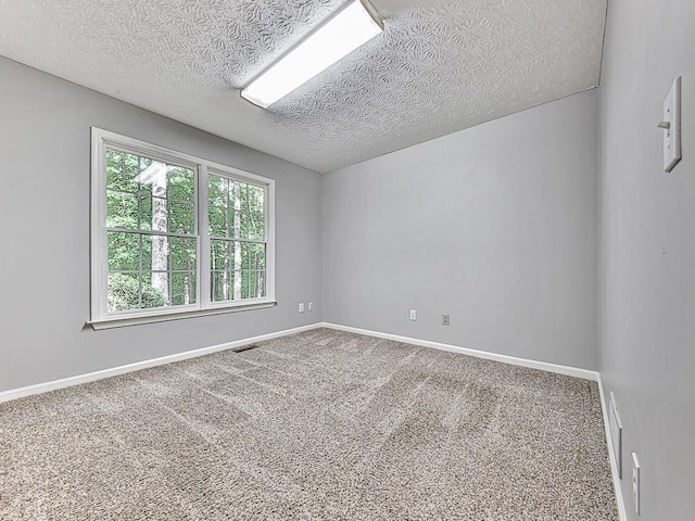 carpeted empty room featuring a textured ceiling