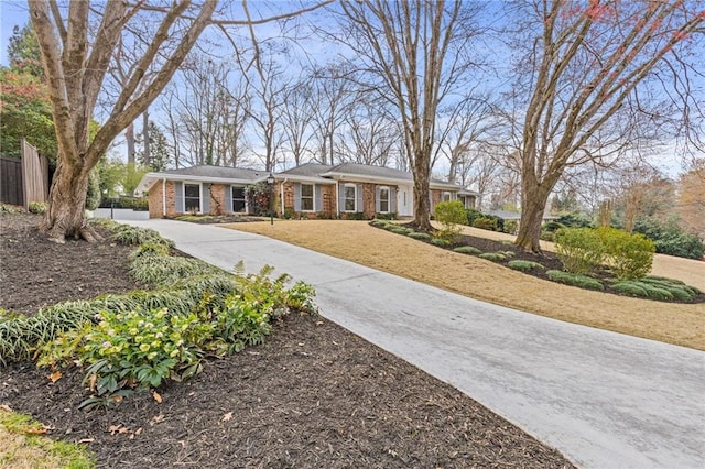 view of front of property with brick siding, concrete driveway, a front yard, and fence