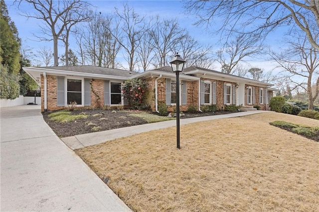 ranch-style house with brick siding, driveway, a front lawn, and fence