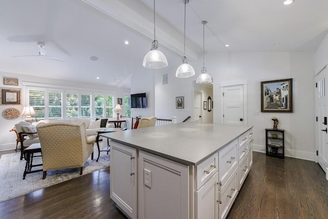 kitchen featuring dark hardwood / wood-style floors, pendant lighting, lofted ceiling with beams, a kitchen island, and white cabinetry