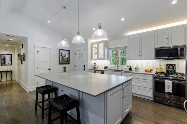 kitchen with range with gas stovetop, a kitchen island, tasteful backsplash, dark wood-type flooring, and lofted ceiling