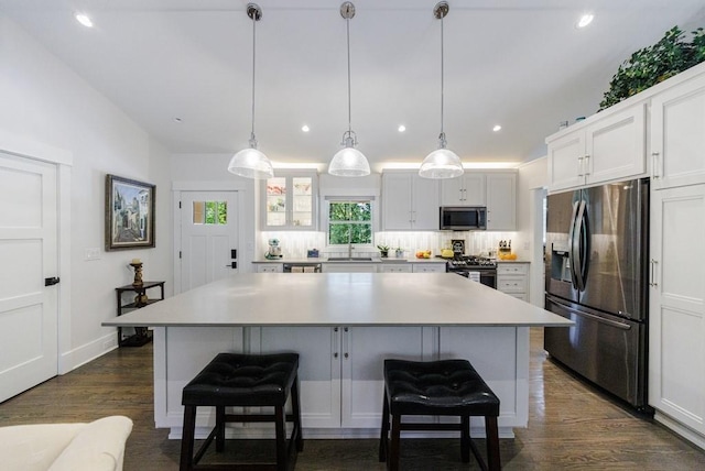 kitchen featuring a center island, white cabinetry, appliances with stainless steel finishes, dark hardwood / wood-style floors, and backsplash