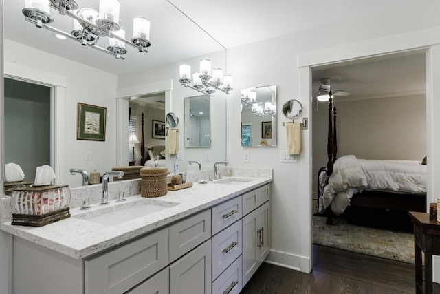 bathroom with dual sinks, hardwood / wood-style flooring, ceiling fan with notable chandelier, and large vanity