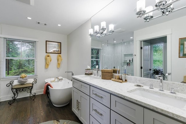 bathroom with a bathtub, dual bowl vanity, a notable chandelier, and wood-type flooring