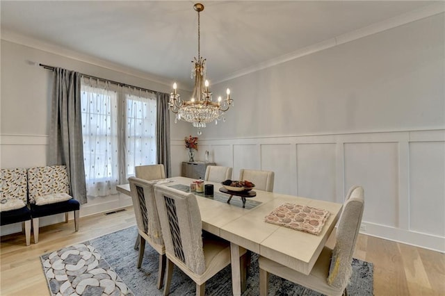 dining area with crown molding, a notable chandelier, and light hardwood / wood-style floors