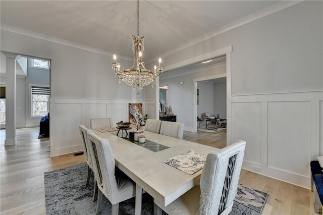 dining room with an inviting chandelier, ornamental molding, and light hardwood / wood-style floors