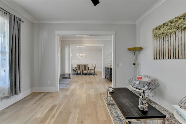 hallway with wood-type flooring, ornamental molding, and an inviting chandelier