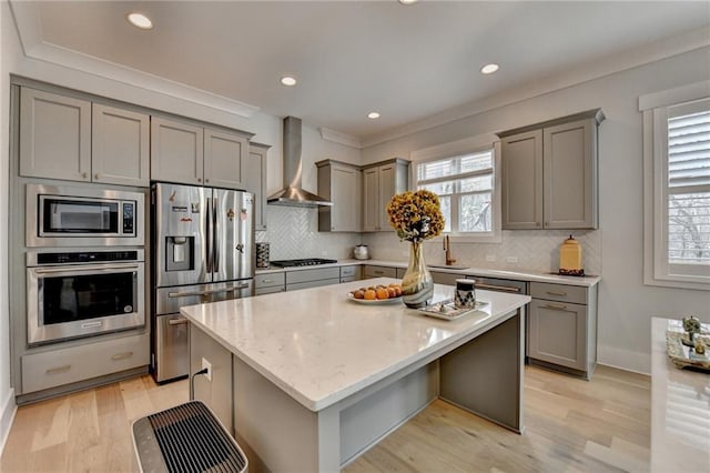 kitchen with wall chimney exhaust hood, a breakfast bar area, light stone counters, appliances with stainless steel finishes, and a kitchen island