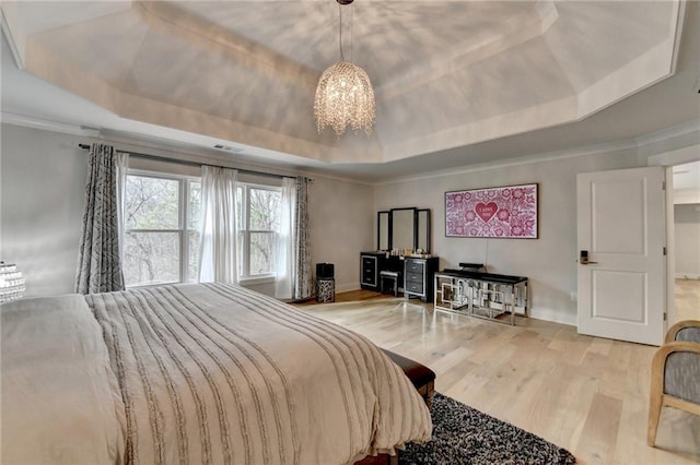 bedroom featuring an inviting chandelier, ornamental molding, a tray ceiling, and hardwood / wood-style floors