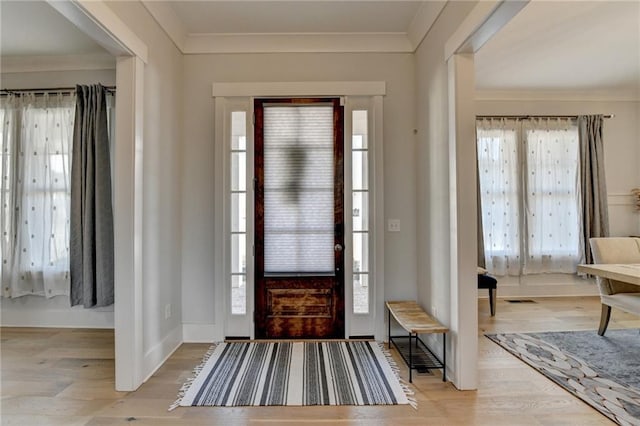 foyer featuring ornamental molding, light hardwood / wood-style flooring, and a wealth of natural light