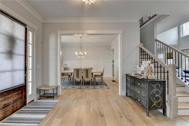 interior space featuring ornamental molding, wood-type flooring, and a notable chandelier